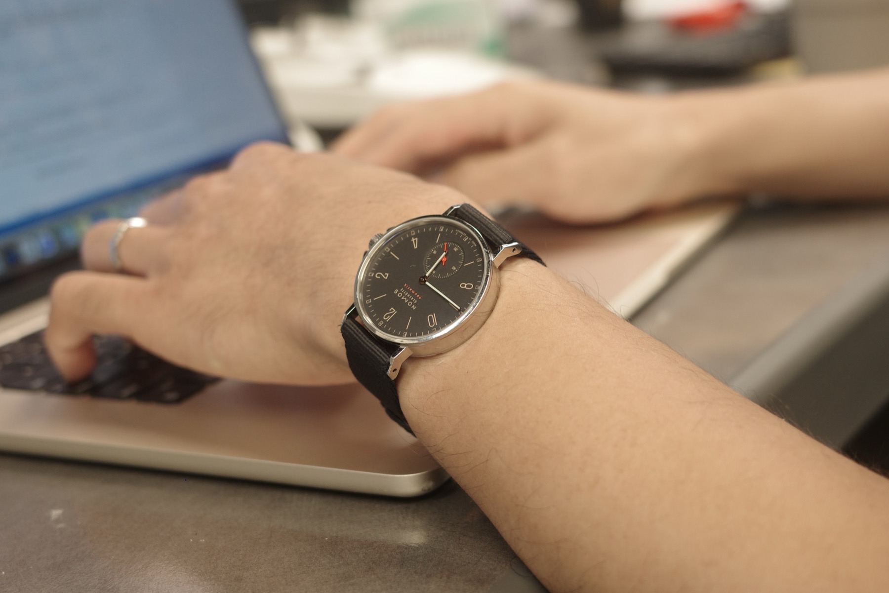 Ahoi on the OEM navy textile strap, wrist on the laptop
